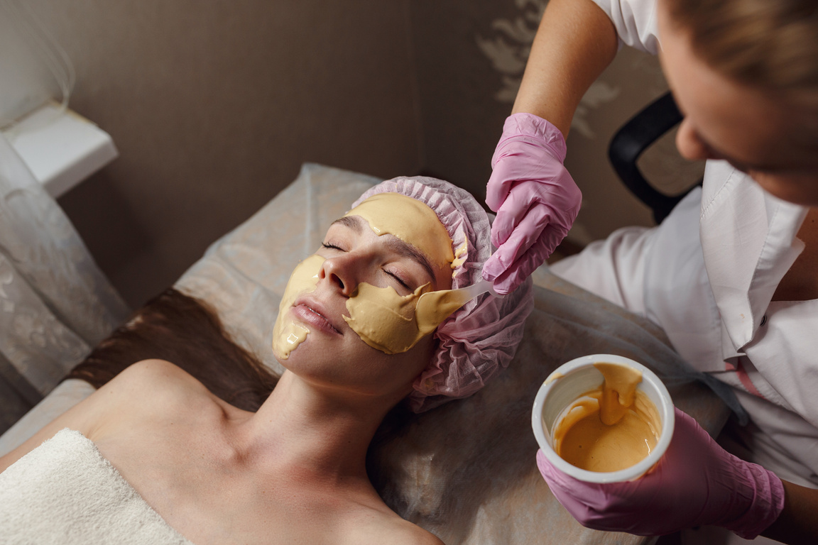 Cosmetology Specialist Applying Gold Facial Mask Using Brush